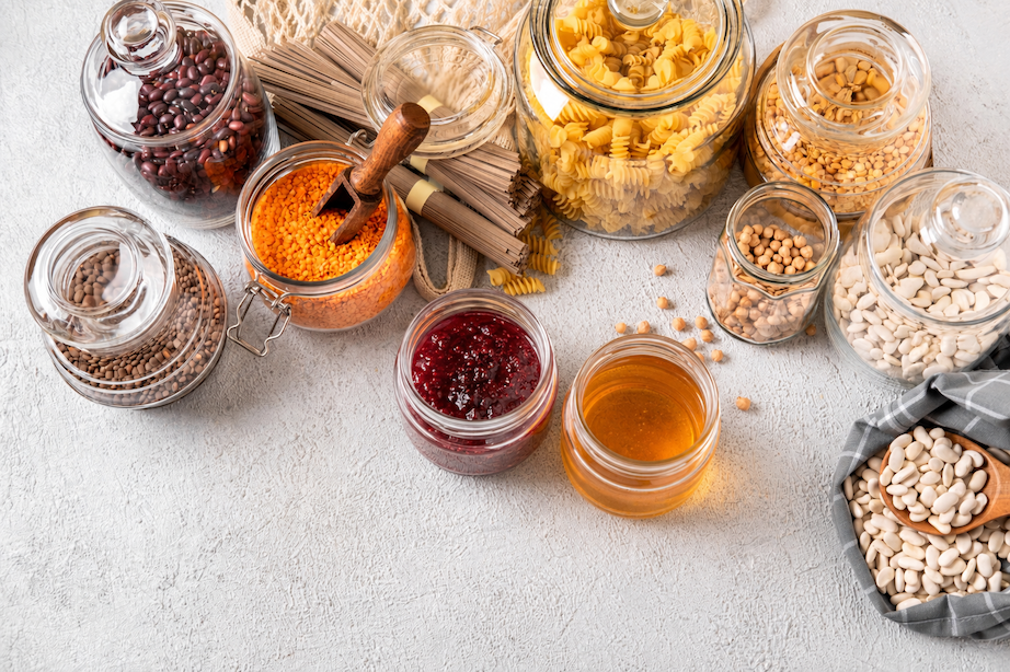 Prodotti da dispensa in barattoli di vetro, con pasta, legumi, miele, conserve e ingredienti secchi