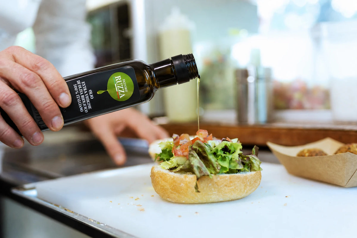 Olio extravergine di oliva biologico Fattorie Ruzza versato su un panino con verdure