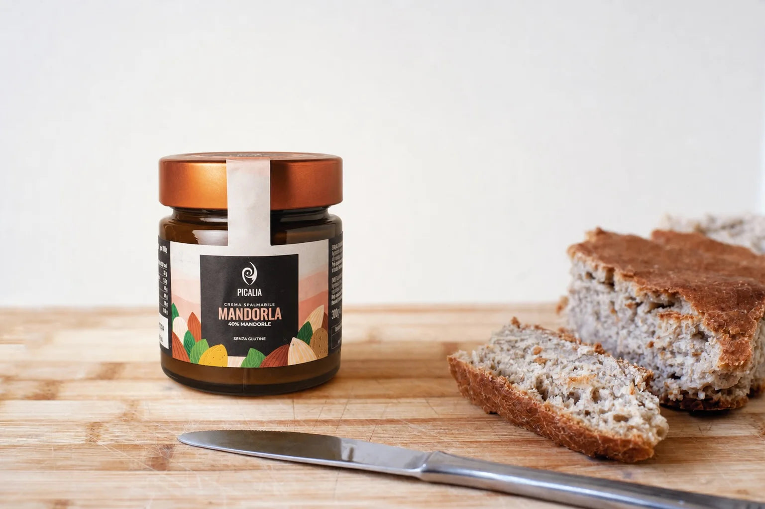 Crema spalmabile alla mandorla Picalia con il 40% di mandorle, accanto a fette di pane su un tagliere.