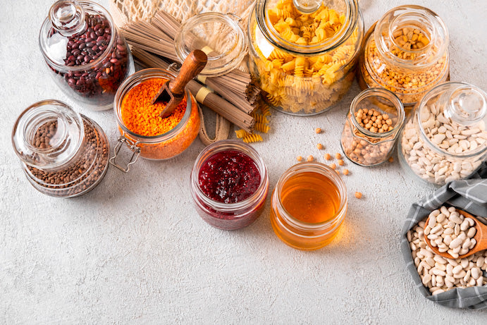 Dispensa con legumi, cereali, spezie e conserve in barattoli di vetro, ideale per prodotti tipici da cucina.